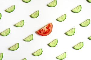 repeating pattern of sliced semicircles of fresh raw vegetable cucumbers for salad and a slice of tomato photo