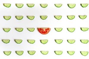 repeating pattern of sliced semicircles of fresh raw vegetable cucumbers for salad and a slice of tomato photo