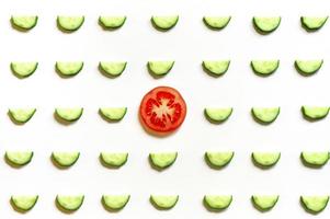 repeating pattern of sliced semicircles of fresh raw vegetable cucumbers for salad and a slice of tomato photo