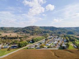 rural neighborhood and farm land in autumn in midwest mountains with trees and open landscape farm fields after harvest family friendly single-family homes and mobile home park for diversity. photo