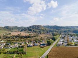 vecindario rural y tierras agrícolas en otoño en las montañas del medio oeste con árboles y campos agrícolas abiertos después de la cosecha Casas unifamiliares para familias y parque de casas móviles para la diversidad. foto