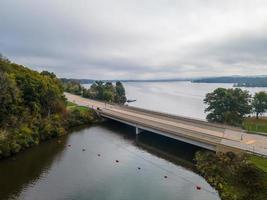 rural bridge over entrance to beautiful lake in midwest at beginning of autumn line of buoys marking safe area trees turning colors photo