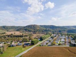 rural neighborhood and farm land in autumn in midwest mountains with trees and open landscape farm fields after harvest family friendly single-family homes and mobile home park for diversity. photo