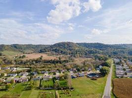 rural neighborhood and farm land in autumn in midwest mountains with trees and open landscape farm fields after harvest family friendly single-family homes and mobile home park for diversity. photo