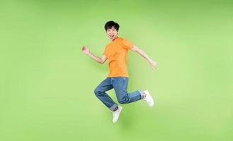 young asian man jumping , isolated on green background photo