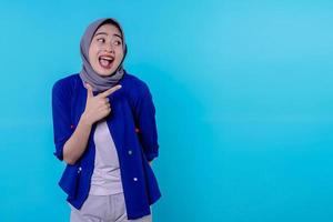 Good looking charismatic young woman with wearing hijab pointing isolated on light blue background photo