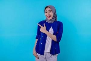 Good looking charismatic young woman with wearing hijab pointing isolated on light blue background photo