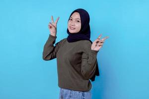 Close-up of happy girl wearing hijab in casual cloth and smiling on blue wall photo