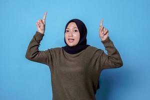 Sonriente mujer asiática feliz con su dedo apuntando aislado sobre fondo de banner azul claro foto