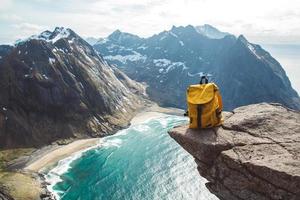 Hiker tourist yellow backpack on rock in mountain, panoramic landscape, traveler relax holiday concept, view planning wayroad in trip vacation, travel adventure photo