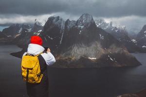 Hombre viajero tomando fotos con un smartphone senderismo en la cresta de la montaña reinebringen en Noruega