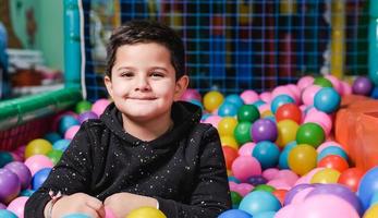 Feliz niño de 5 años con máscara en una piscina de bolas tan feliz foto