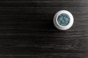 Generic blue erectile dysfunction pills in a bottle on wood background. View with copy space. photo