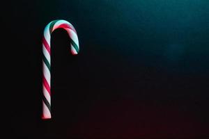 Minimal Christmas composition. Greeting card template with candy cane on dark background. photo