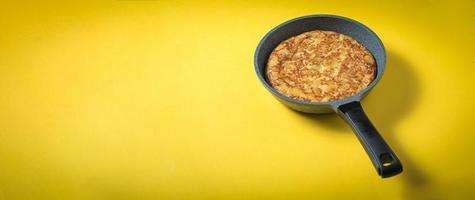 tortilla de patatas sobre fondo amarillo, plato típico español. copia espacio para texto y vista superior foto