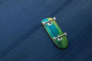 Fingerboard. A small skateboard for kids and teenagers to play with hand fingers. Isolated on blue wood background photo