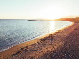 Girl and dog at the beach at sunset, Aerial Views photo