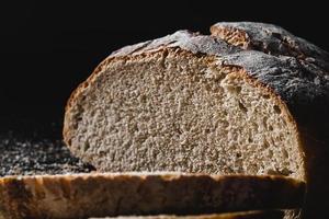 Sliced loaf of dark homemade bread dusted with flour