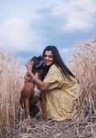 Happy young man hugging his dog while enjoying the day together outdoors in a wheat field. photo