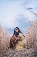 Portrait of a young woman hugging her dog in the middle of a wheat field. Nature and animals concept photo