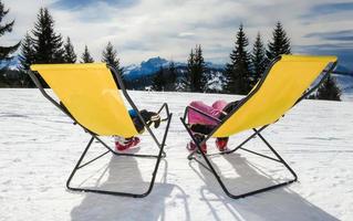 Two children on the lounge chairs on mountain photo