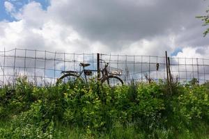An old bicycle on a background of clouds standing alone in the field. photo