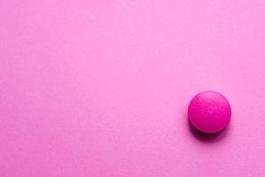 Pink tablet on a pink table close-up. Medical theme. photo