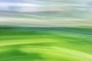 Green fields and sky. Spring summer landscape. Abstract background. The photo was taken with the movement of the camera at a long exposure.