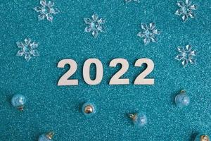 Números de madera año nuevo 2022 con decoración navideña sobre fondo azul brillante