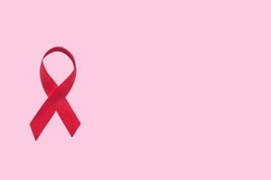 Red ribbon symbol of world aids day on pink background photo