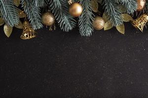Christmas layout with Christmas trees, gold baubles and bells on black background photo