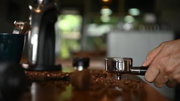 The barista is preparing the ground coffee to make espresso for the customers in the morning. video