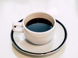 café caliente en taza blanca servido en un café muy tranquilo. foto