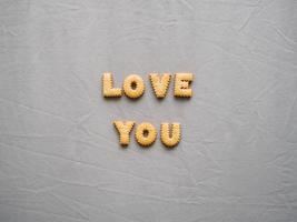 Bicuits arrange into words on grey background. Concept of word LOVE YOU. photo