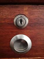 The keyhole on the drawer of wooden table photo