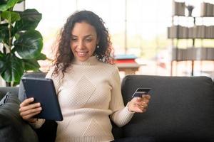 Latin woman using tablet and hand holding credit card photo