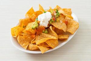 nachos tortilla chips with jalapeno, guacamole, tomatoes salsa and dip photo