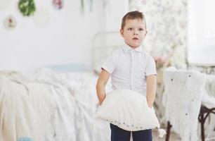 niño pequeño en camisa blanca con almohada