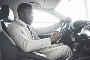 Stylish black businessman sitting behind the wheel of new luxury car. Rich african american man photo