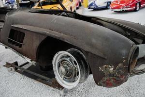 old rusty retro car bumper lies on the white rock surface in the auto show photo