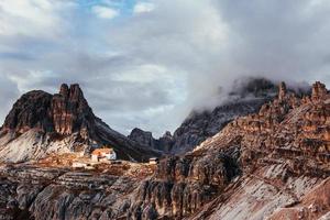 Sunlight barely gets through the thick clouds. Touristic buildings waiting for the people who wants goes through these amazing dolomite mountains photo