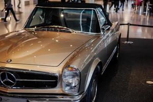 STUTTGART, GERMANY - OCTOBER 16, 2018 Mercedes Museum. Many visitors at room. Auto show. Brown luxury sedan parked on the black floor photo