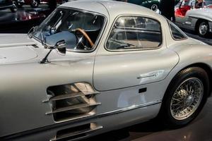 Left side of retro automobile. Old silver shiny car standing indoor at vehicle exhibition