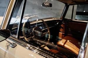 Inside of the classic creamy colored automobile. Steering wheel and front seats photo