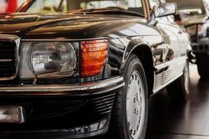 Front part of classical black automobile parked indoor at car show photo