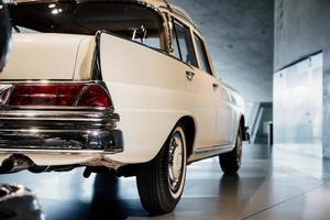 Close up view. Rear part. Cropped image of white classic rare car parked indoor on the tile photo