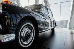 Shiny look. Ground view. Front left side of rare car standing on black tile indoors photo