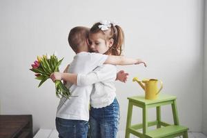 hermoso niño y niña con tulipanes con abrazo. día de la madre, 8 de marzo, feliz cumpleaños foto