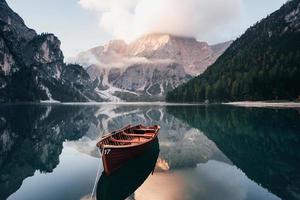 es el momento de la aventura. barco de madera en el lago de cristal con majestuosa montaña detrás. reflejo en el agua