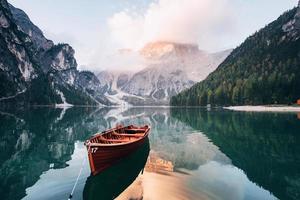 hermoso entorno. barco de madera en el lago de cristal con majestuosa montaña detrás. reflejo en el agua foto